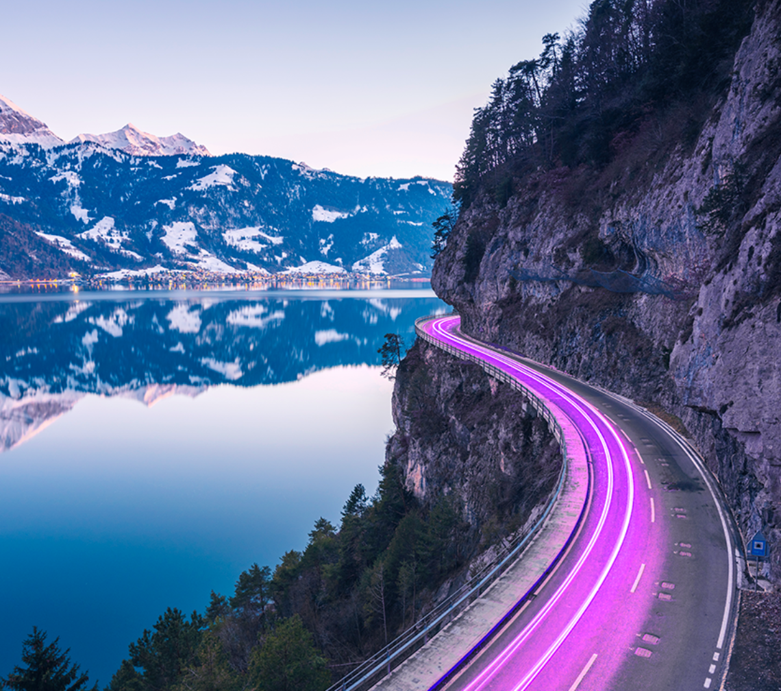 Light streaks winding around a lake with mountains in the distance